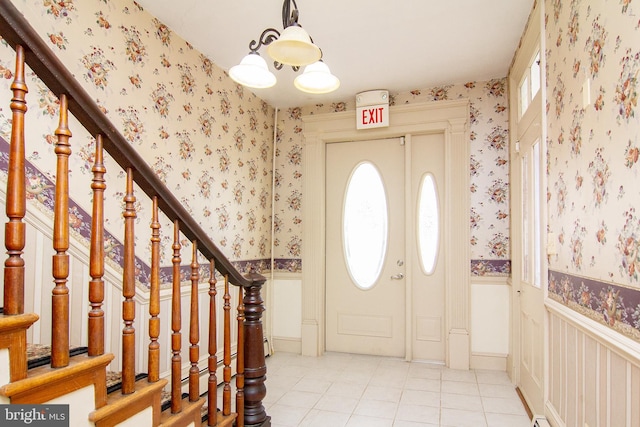foyer with light tile patterned floors, stairway, wainscoting, and wallpapered walls