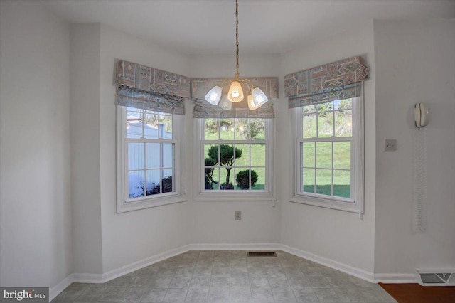 unfurnished dining area featuring baseboards, visible vents, and a notable chandelier