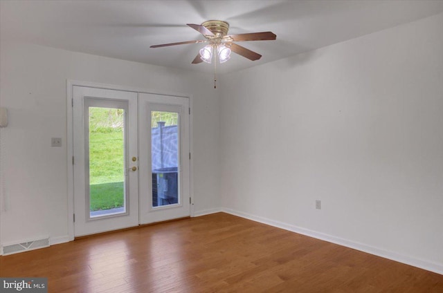 unfurnished room featuring visible vents, wood finished floors, baseboards, french doors, and a ceiling fan