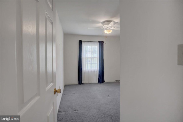 empty room featuring a ceiling fan and carpet