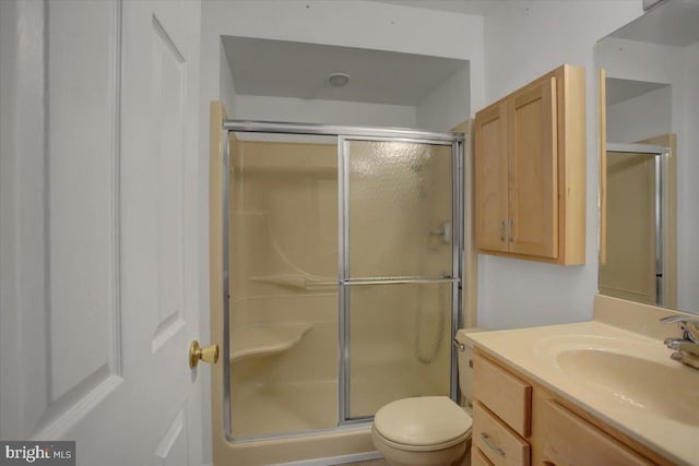 bathroom with vanity, a shower stall, and toilet