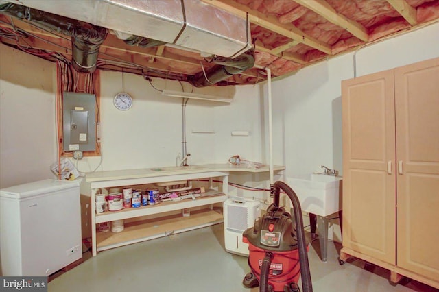 unfinished below grade area featuring a sink, electric panel, and fridge