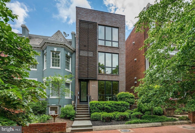 contemporary home featuring brick siding and a high end roof