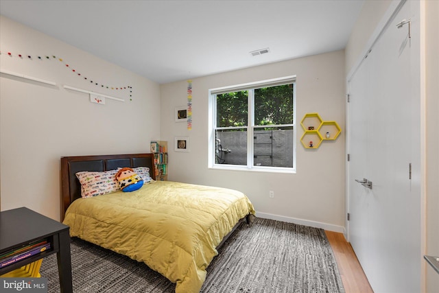 bedroom featuring baseboards, wood finished floors, and visible vents