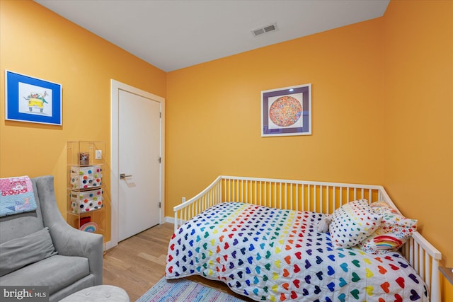 bedroom with baseboards, visible vents, and wood finished floors