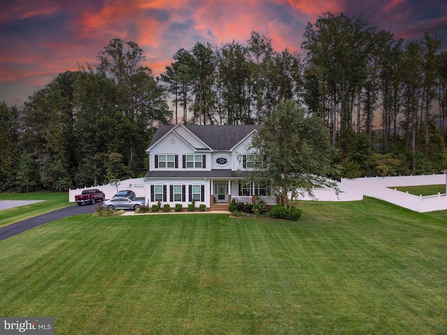 view of front of property with a porch, fence, driveway, and a front lawn