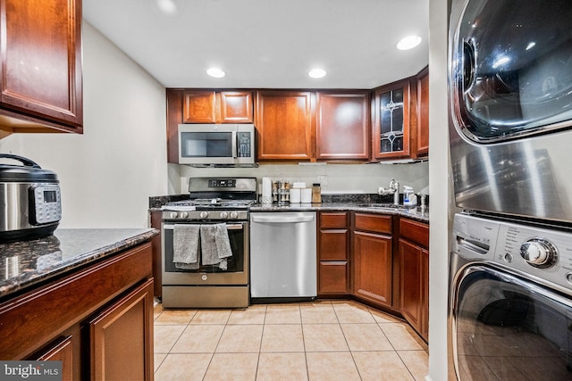 1423 Northgate Sq Unit 1423-11C, Reston, VA 20190 - kitchen featuring appliances with stainless steel finishes, stacked washer / dryer, a sink, dark stone countertops, and light tile patterned floors