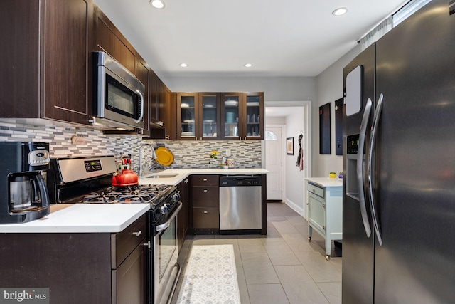 kitchen featuring backsplash, dark brown cabinets, a sink, light countertops, and stainless steel appliances