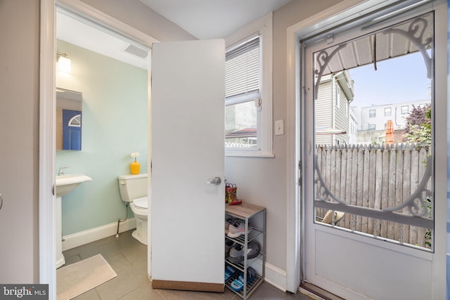 doorway to outside with baseboards, visible vents, and tile patterned floors