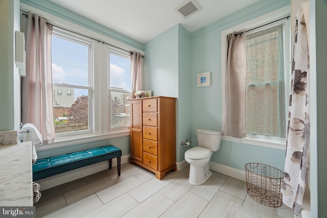 full bath with toilet, baseboards, and visible vents