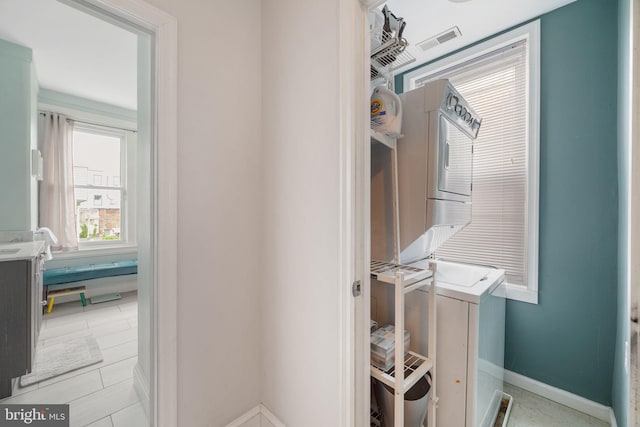 washroom featuring laundry area, stacked washer / drying machine, baseboards, and visible vents