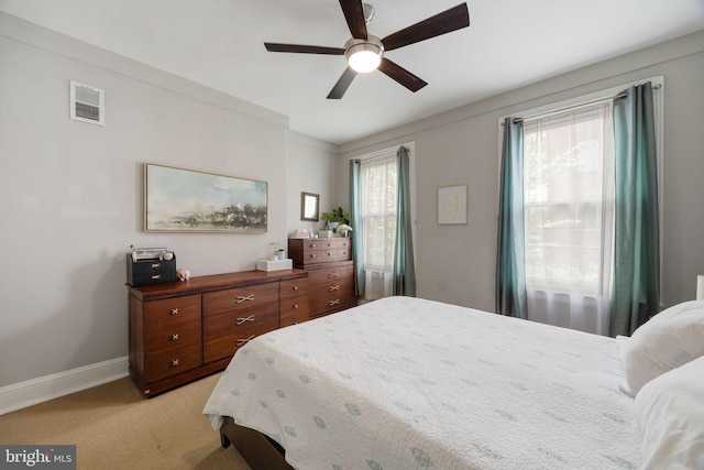 bedroom with baseboards, light carpet, a ceiling fan, and visible vents