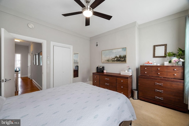 bedroom featuring crown molding, a ceiling fan, light colored carpet, and visible vents