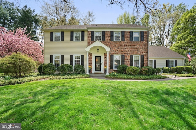 colonial inspired home with brick siding and a front lawn