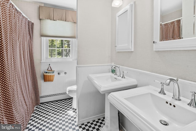 full bathroom featuring curtained shower, toilet, baseboard heating, tile patterned floors, and a sink