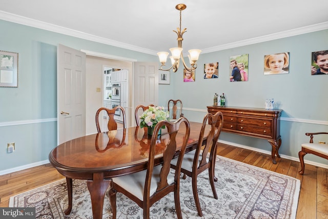 dining area with crown molding, baseboards, a chandelier, and wood finished floors