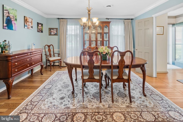 dining space featuring an inviting chandelier, ornamental molding, a wealth of natural light, and light wood-style floors