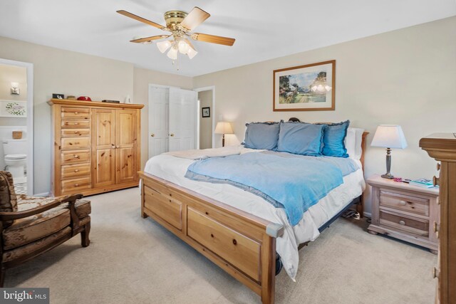 bedroom featuring ensuite bathroom, a ceiling fan, and light carpet