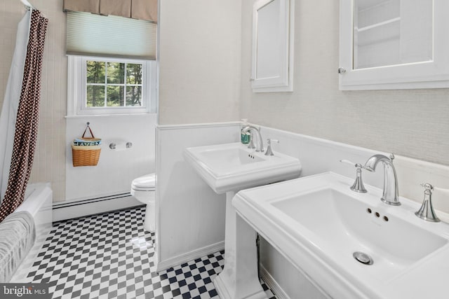 bathroom featuring baseboard heating, wainscoting, a sink, tile patterned floors, and toilet
