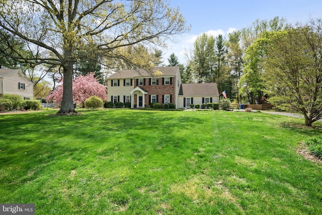 colonial-style house featuring a front lawn and brick siding