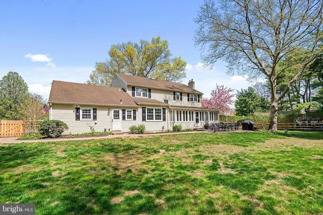 back of house featuring a lawn, fence, and a chimney