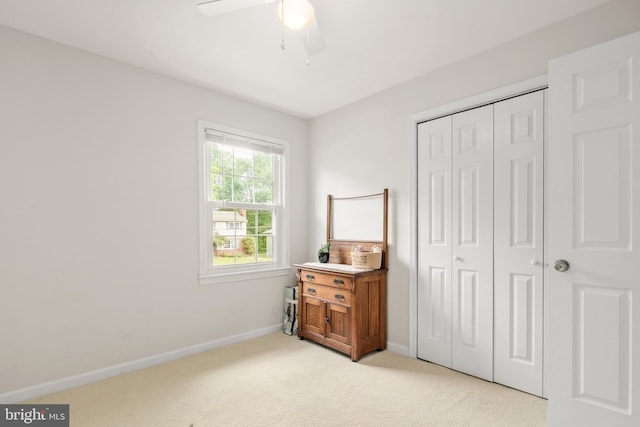 bedroom featuring baseboards, a ceiling fan, a closet, and light colored carpet