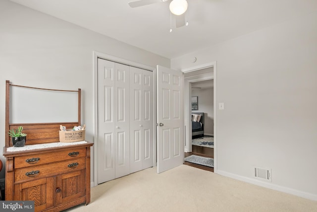 bedroom featuring ceiling fan, visible vents, light colored carpet, baseboards, and a closet