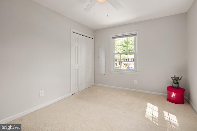 unfurnished bedroom featuring baseboards, ceiling fan, carpet, and a closet