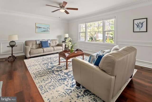 living area featuring ornamental molding, wainscoting, a decorative wall, wood finished floors, and a ceiling fan