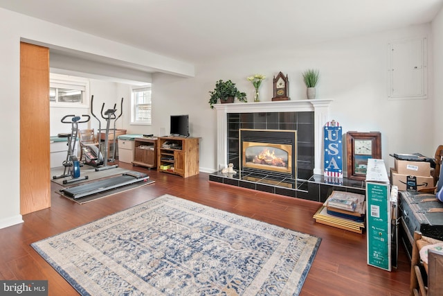 interior space with a tiled fireplace, electric panel, and wood finished floors