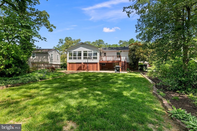 rear view of property with a yard, a wooden deck, stairs, and a sunroom