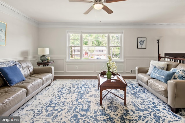 living area featuring crown molding, visible vents, wood finished floors, a wainscoted wall, and a ceiling fan