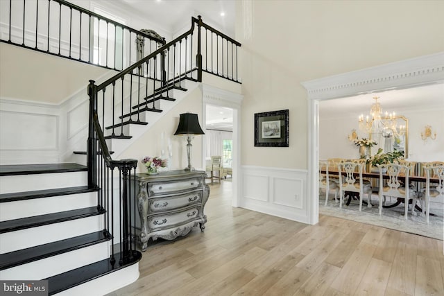 1071 Highland Rd, Newtown, PA 18940 - stairs featuring a decorative wall, wood finished floors, a towering ceiling, a chandelier, and a wainscoted wall