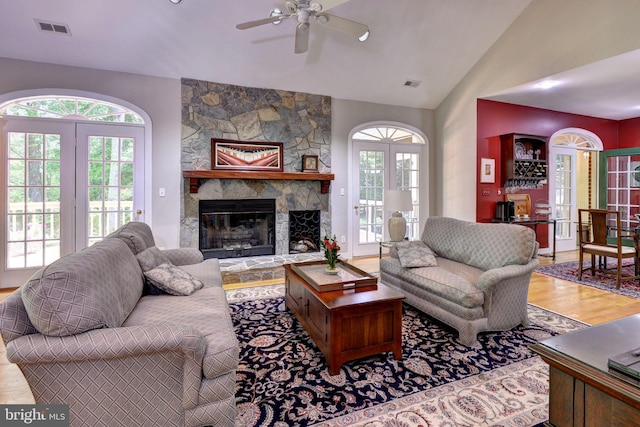 living area with vaulted ceiling, a ceiling fan, wood finished floors, and visible vents