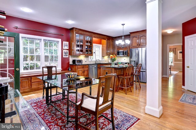 dining area with a notable chandelier, decorative columns, baseboards, and light wood-style floors