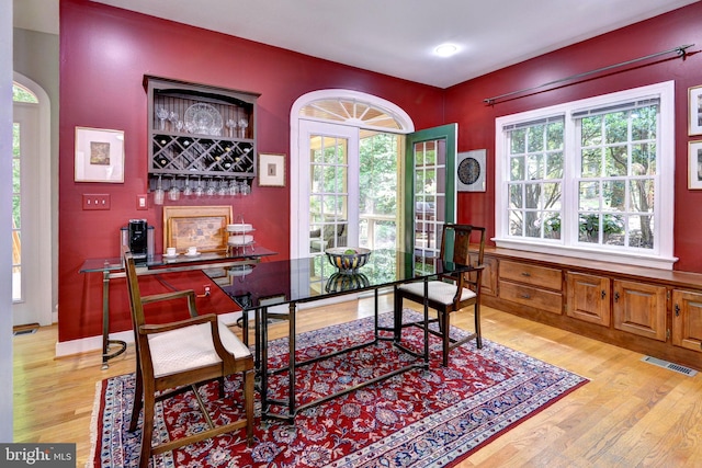 home office featuring light wood-style floors, a dry bar, and visible vents