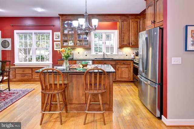 kitchen featuring brown cabinetry, light wood-style floors, a center island, a sink, and stainless steel appliances