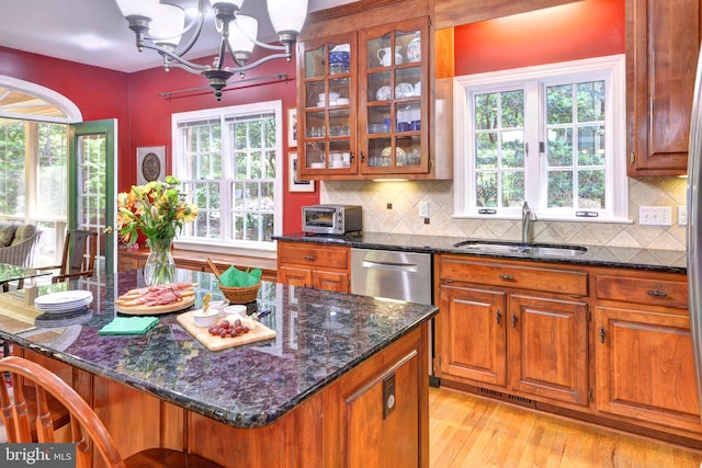 kitchen with brown cabinets, a chandelier, a sink, and dark stone countertops