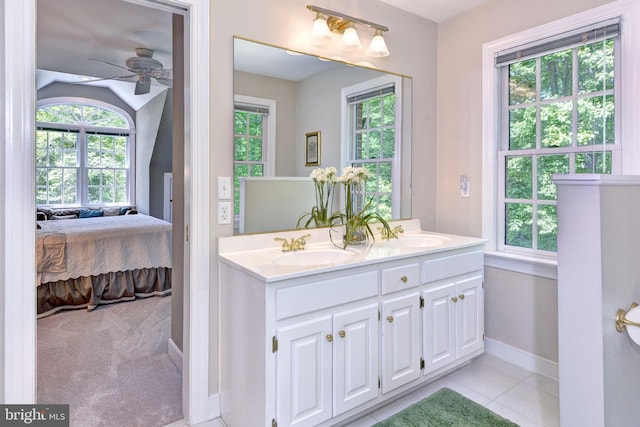 ensuite bathroom featuring connected bathroom, ceiling fan, a sink, baseboards, and a healthy amount of sunlight