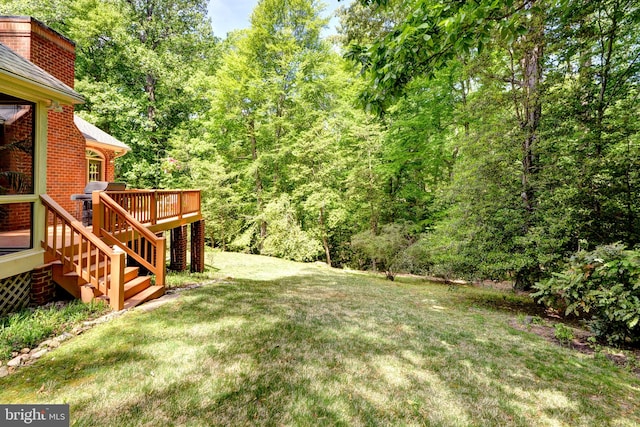 view of yard with stairway, a deck, and a view of trees