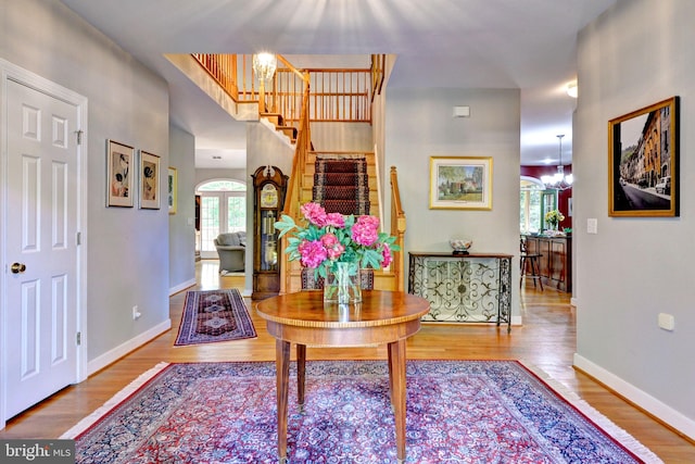 foyer featuring an inviting chandelier, baseboards, wood finished floors, and stairway