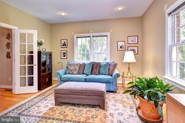 living area with baseboards, plenty of natural light, wood finished floors, and visible vents
