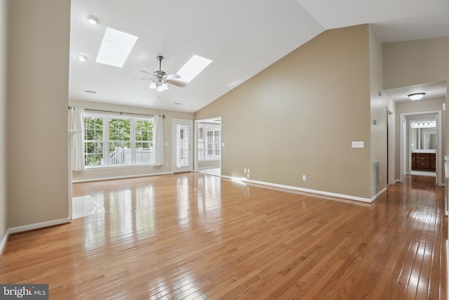 unfurnished living room with a skylight, baseboards, light wood-type flooring, and high vaulted ceiling