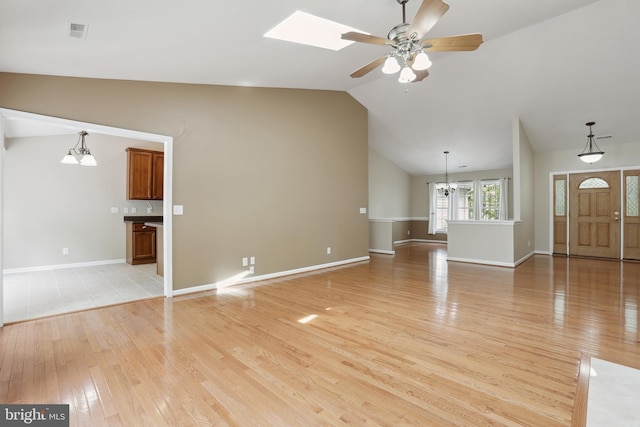 unfurnished living room with light wood-style floors, ceiling fan with notable chandelier, baseboards, lofted ceiling, and visible vents