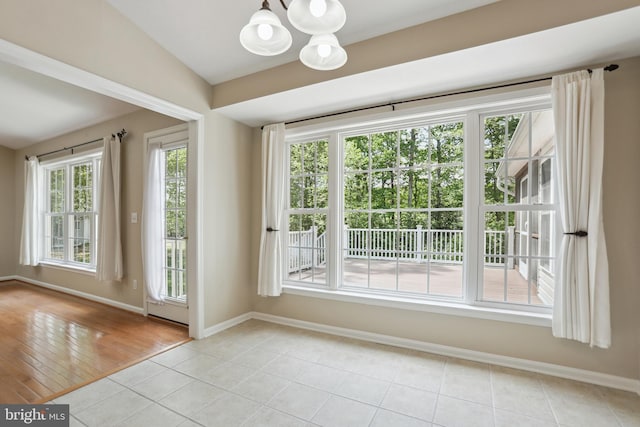 doorway to outside featuring light tile patterned flooring, baseboards, an inviting chandelier, and lofted ceiling