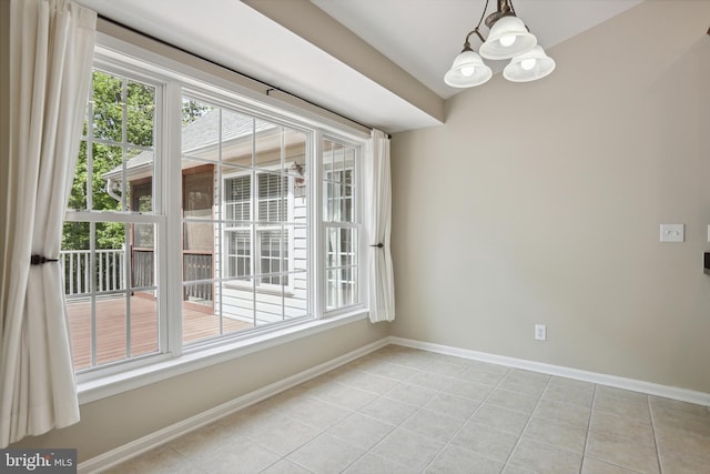 unfurnished dining area with light tile patterned floors, baseboards, plenty of natural light, and a chandelier