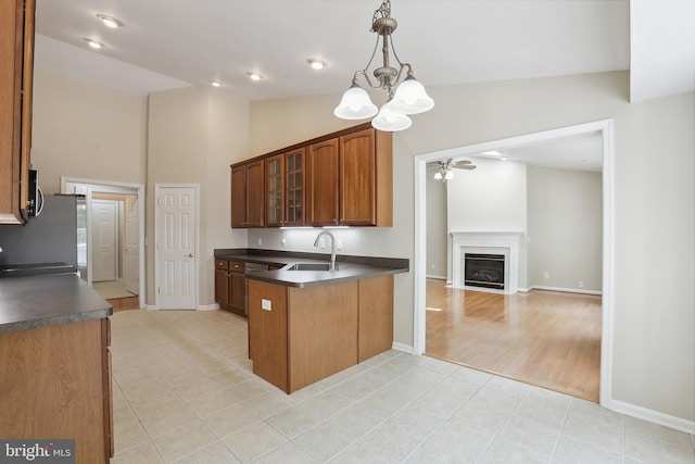 kitchen featuring a peninsula, dark countertops, glass insert cabinets, and a sink