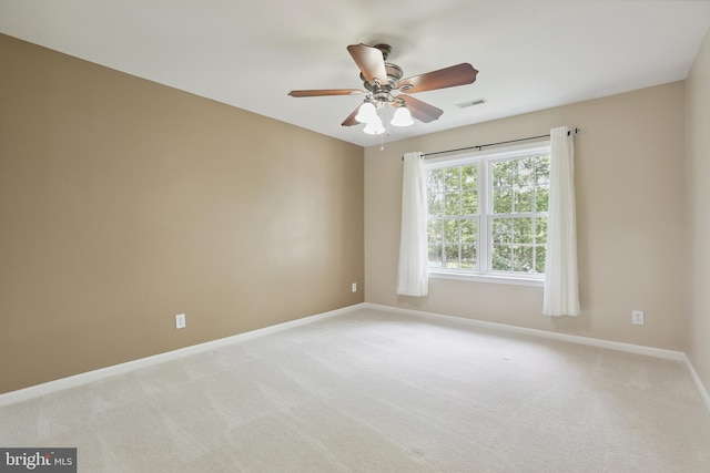 spare room featuring baseboards, ceiling fan, light colored carpet, and visible vents