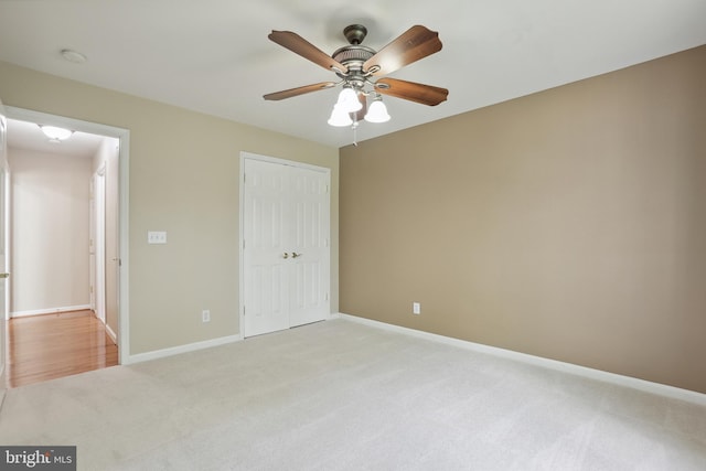 unfurnished bedroom with baseboards, light carpet, ceiling fan, and a closet