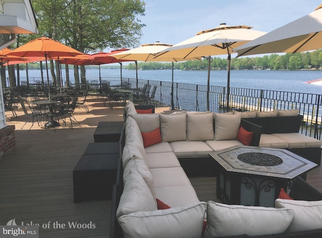 view of patio with a water view and an outdoor living space with a fire pit